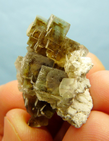 A cluster of greyish-brown fluorite crystals, some with darker centres and patterns inside