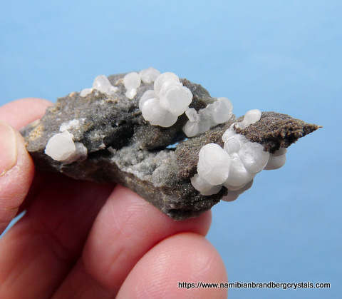 Pearly aggregates of smithsonite sit on rock matrix
